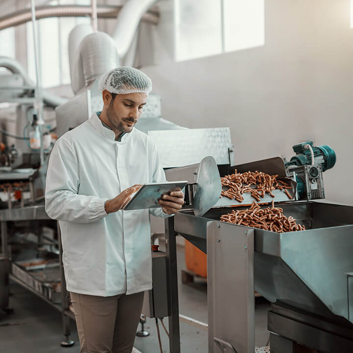 oung-Caucasian-serious-supervisor-evaluating-quality-of-food-in-food-plant-while-holding-tablet-