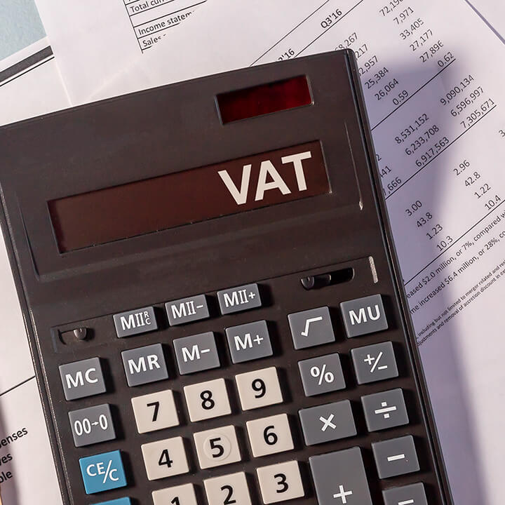 VAT word on display of calculator on papers documents and golden pen